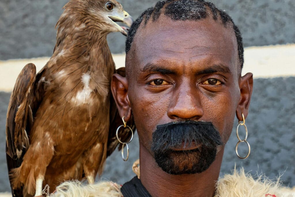 Une personne avec un oiseau qui lui picore dans la tête...